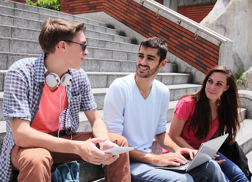 Studentin und Studenten bei der Arbeit am Laptop in heiterer Stimmung