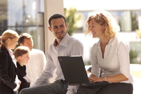 Studentin und Student bei der Arbeit am Laptop in heiterer Stimmung