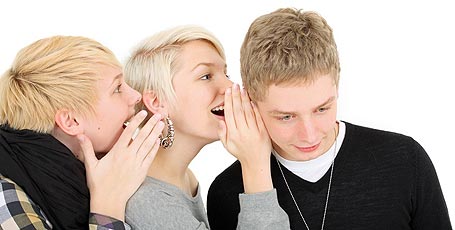 Drei Schüler flüstern sich ins Ohr