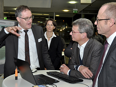 Prof. Dr. Marco Linß von der HaW Hof erklärt Wissenschaftsminister Bernd Sibler (2.r.) und dem stellvertretenden bayme vbm vbw Hauptgeschäftsführer Dr. Christof Prechtl (r.) das Hofer Notenmonitoringprogramm
