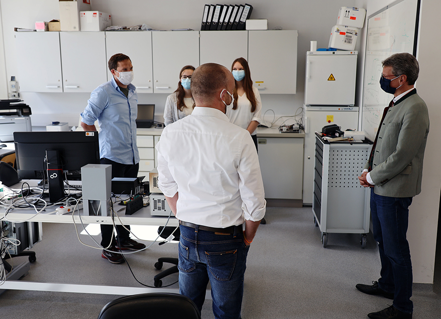 Wissenschaftsminister Bernd Sibler mit Studentinnen und Studenten der HAW Landshut, die Halterungen für Gesichtsvisiere herstellen (Foto: HaW Landshut)