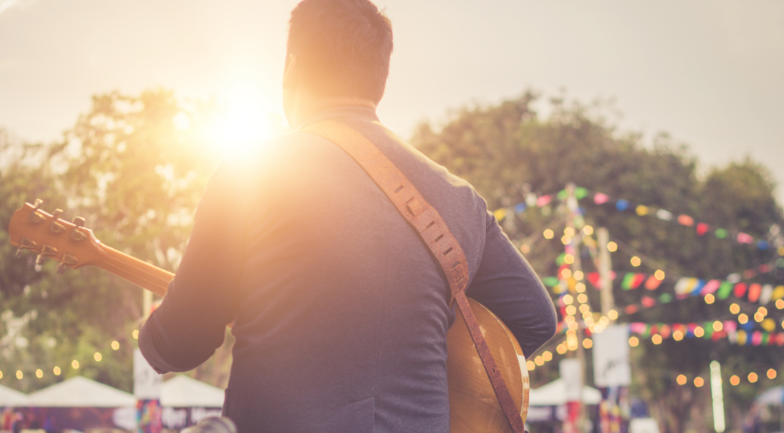 Ein Musiker spielt auf einer Bühne im Freien Gitarre